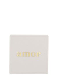 Vit fyrkantig tvål med ordet "amor" präglat i guldbokstäver centrerat på ytan.