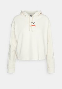 Hoodie cropped color crema, realizzato in tessuto morbido. Presenta un cappuccio con coulisse e un piccolo logo Puma nero con dettagli rossi al centro.