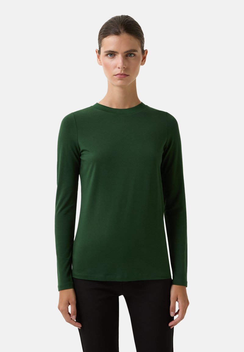 Haut à manches longues, col rond en tissu vert foncé, texture lisse, design ajusté, détails minimalistes, associé à un pantalon noir.