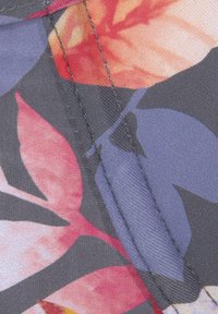 Stoffen met bloemenpatroon in tinten van rood, blauw en grijs, met een gladde textuur en zichtbare stiksels langs de randen.