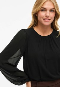 Blusa nera con maniche lunghe e trasparenti e scollatura rotonda. Tessuto liscio con un delicato dettaglio arricciato nella scollatura.