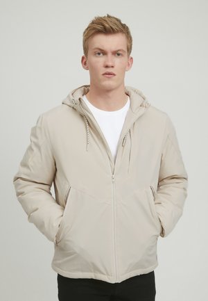 Beige insulated jacket with a zipper, adjustable hood, and side pockets. Smooth texture with seam detailing on shoulders and chest.
