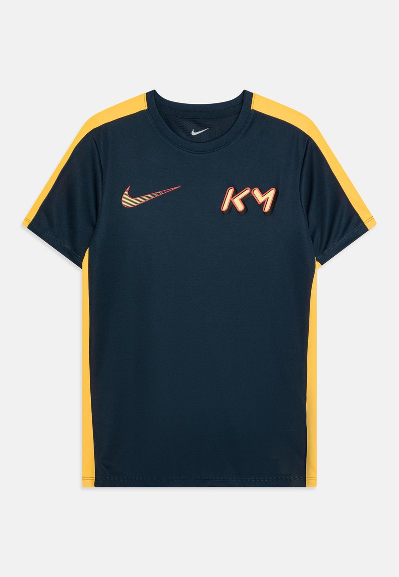 Camisa deportiva azul marino con acentos amarillos en los hombros, que presenta un logo de Nike en rojo y "KM" en letras con estilo 3D en la parte delantera.