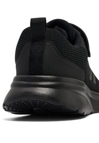 Czarne buty sportowe z teksturowaną syntetyczną cholewką, detalami z siateczki, wyraźną pętlą na pięcie i gumową podeszwą z okrągłym wzorem bieżnika.