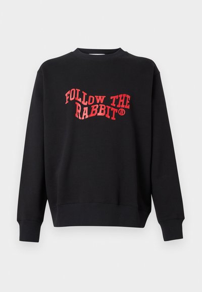 Sort sweatshirts med ribbede manchetter og kant, der pryder teksten "FOLLOW THE RABBIT" i fed rød buet skrift på forsiden.