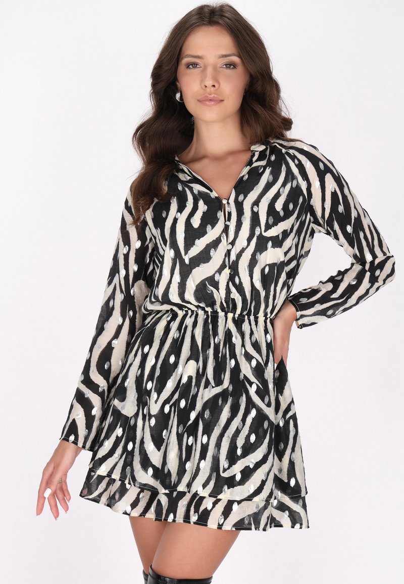Schwarz-weißer, abstrakter gemusterter Kleid mit langen Ärmeln, einem Kragen und einer Empire-Taille, das einen gestuften Rock und einen leichten Glanz aufweist.