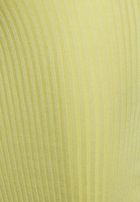 Tecido texturizado com finas riscas verticais numa cor amarelo claro com um ligeiro brilho, realçando um material suave e elástico.