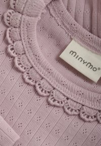 Liliowy sweter dziany z teksturowanym, prążkowanym wzorem oraz dekoracyjnym koronkowym wykończeniem w kształcie falbany wokół dekoltu. Zawiera metkę "Minymo".