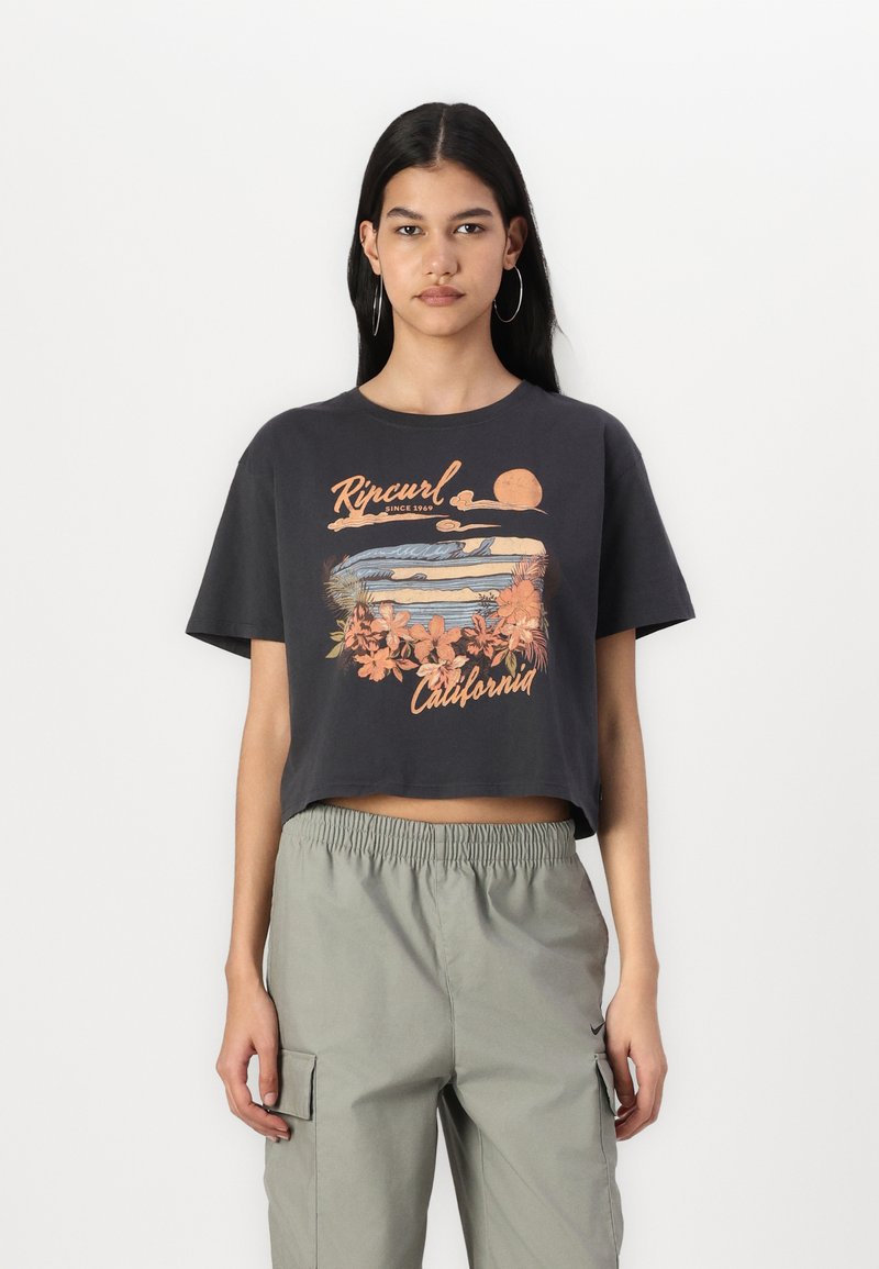 Korte zwarte t-shirt met een meerkleurige afbeelding met bloemen elementen en tekst. Gecombineerd met lichtgrijze cargobroek.