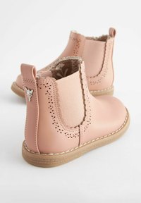Botines de cuero rosa hasta el tobillo con paneles elásticos, bordes en forma de ondas, perforaciones decorativas y una suela de goma beige.