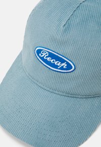 Light blue corduroy cap with a curved brim and embroidered "Recap" logo in blue and white. Features vertical ribbed texture.