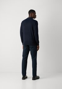 Navy long-sleeve sweater with a textured finish, paired with dark pants, and black shoes. The sweater features a ribbed hem and cuffs.