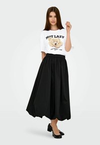 White T-shirt with a teddy bear graphic and text, paired with a black, ankle-length skirt featuring an elastic waistband and flowing design.