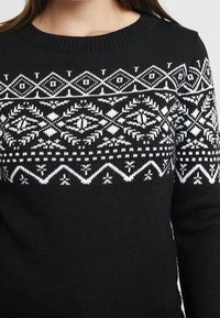 Schwarzer Strickpullover mit einem weißen, geometrischen und abstrakten Muster auf Brust und Ärmeln, ausgestattet mit einem klassischen Rundhalsausschnitt.