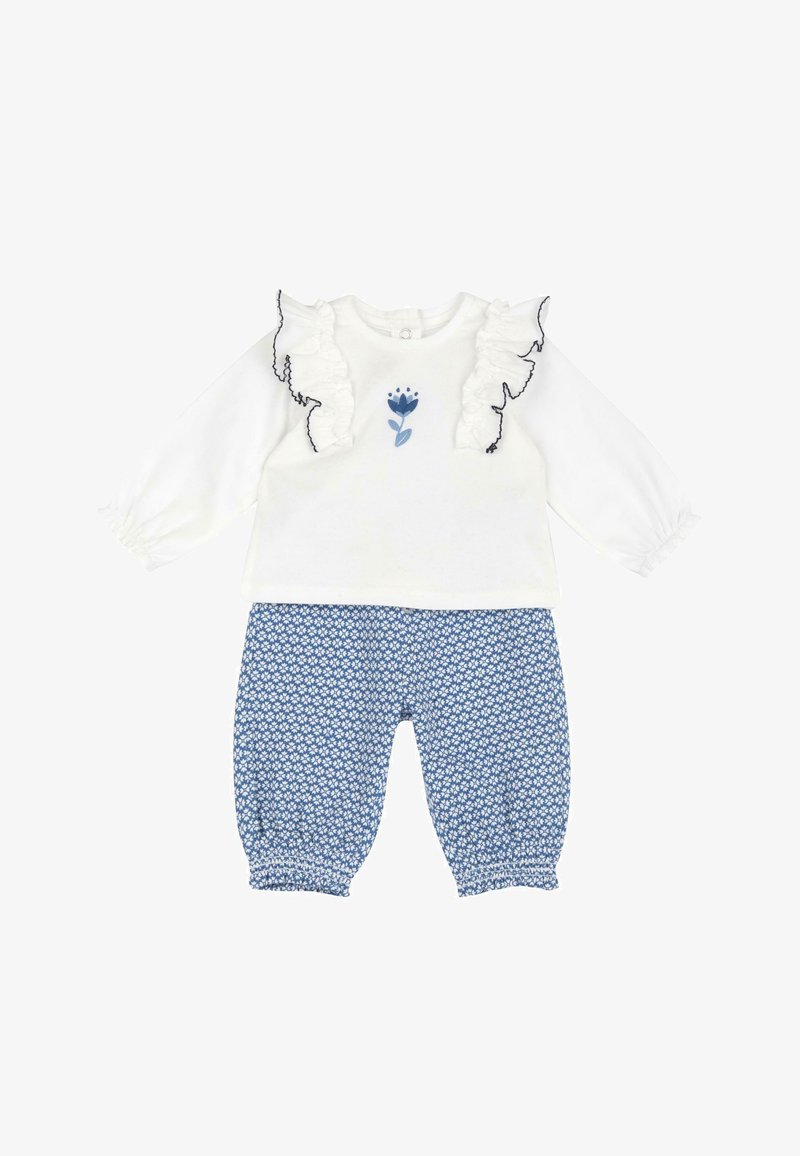 Top bianco a maniche lunghe con maniche arricciate e ricamo floreale, abbinato a pantaloni blu a fantasia con polsini elasticizzati.