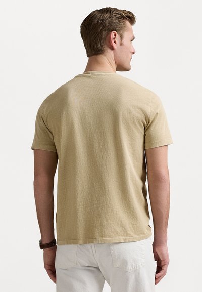 Μπλούζα με κοντά μανίκια σε μπεζ απόχρωση, με υφή, κλειστή λαιμόκοψη και ευθεία ραφή. Ελάχιστες ραφές με πιο άνετη εφαρμογή.