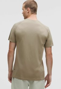 Kurzärmliges, helles Taupe-T-Shirt aus strukturiertem Stoff, mit Raglanärmeln und rundem Ausschnitt. Verfügt über ein kleines Logo nahe dem Saum.