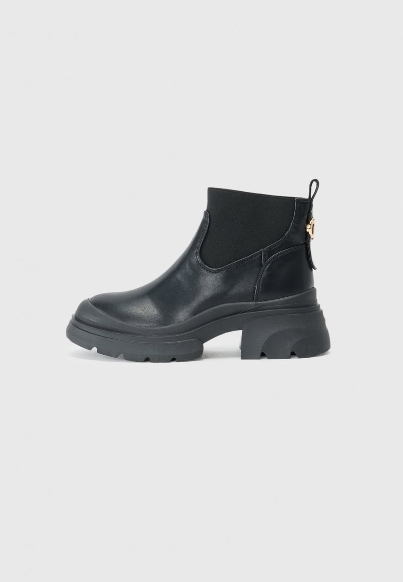 Bottines en cuir noir avec une semelle en caoutchouc épaisse, des panneaux latéraux élastiques et une languette. Texture lisse avec un design minimaliste.