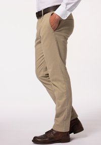 Beige chino's met een rechte pijp, voorzien van zijzakken en een gladde textuur, gecombineerd met bruine leren veterschoenen.