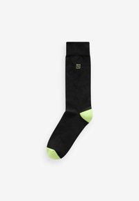 Black sock featuring a green accent at the heel and toe, with a small green logo on the side; smooth texture and knee-high design.