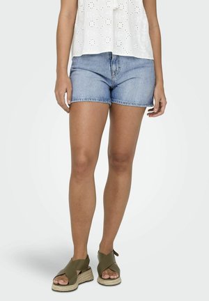 Shorts en denim avec un lavage bleu clair, dotés d'un design classique à cinq poches et d'un ourlet effiloché. Associés à des sandales espadrilles vert olive.