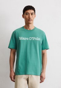 Groene katoenen T-shirt met een ronde hals, korte mouwen en een wit "Marc O’Polo" logo gedrukt op de voorkant. Glad textuur, ontspannen pasvorm.
