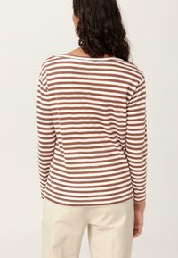 Camisa de manga larga a rayas marrón y blanca con un escote amplio, hecha de material suave, vista desde la parte de atrás.