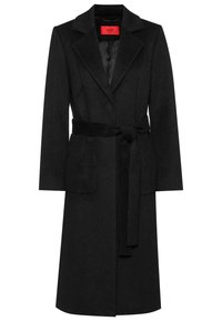 Manteau noir en mélange de laine, avec une coupe ajustée, des revers à cran, deux poches avant et une ceinture assortie à la taille. Doublure intérieure.