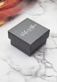 Scatola per gioielli nera con texture, dotata di coperchio a cerniera, con logo stampato in bianco "Sofia Milani Jewels" sulla superficie superiore.