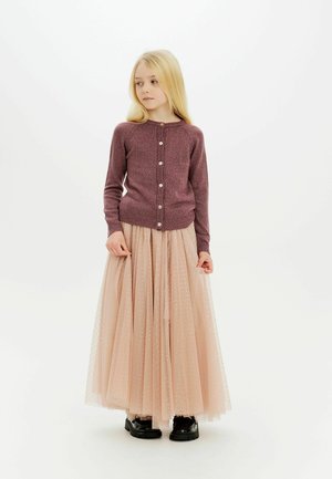 Burgundy stickad cardigan med knappar och ribbad fåll, tagen med en lager-på-lager tullekjol i ljusrosa med glittrande detaljer och svarta skor.