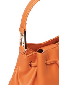 Borsa a mano arancione in pelle con una texture liscia, dotata di una chiusura in metallo dorato e di un sistema di chiusura a cordoncino per un accesso regolabile.