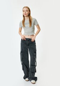 Harmaa ribbed lyhyt toppi, jossa on "Oregon Portland" -teksti, yhdistettynä mustiin cargo-housuihin, joissa on sivutaskut ja jotka on valmistettu denim-kankaasta.