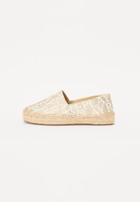 Scarpa espadrilla in tela beige con grandi lettere bianche. Presenta una soletta in corda di juta e punta rotonda. Design minimalista senza ulteriori accenti.