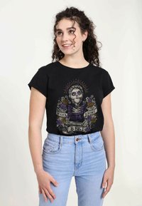 Černé tričko s živou grafikou skeletonu s květinovými akcenty, textové prvky jsou "Mama ví nejlépe" na volném střihu.