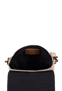 Petit sac bandoulière beige avec ouverture sur le dessus montrant l’intérieur noir et un patch en daim à l’intérieur, vu de dessus.