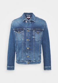 Denimová bunda ve středně modrém odstínu s knoflíkovým zapínáním vpředu, dvěma náprsními kapsami a ozdobnými švy; klasický límec a dlouhé rukávy.