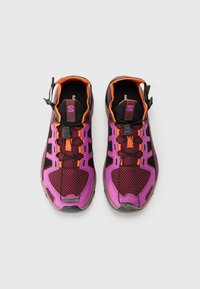 Lila und schwarze Sportschuhe mit einem Obermaterial aus Mesh, orangen Akzenten, einem Slip-On-Design und einem Schnürsystem mit Zugmechanismus. Gummisohle und strukturierte Oberfläche.
