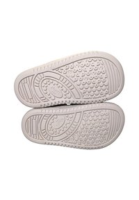 Sole delle scarpe in gomma beige chiaro con motivi antiscivolo testurizzati. Presenta bordi arrotondati e dettagli con logo marchiato sul fondo.