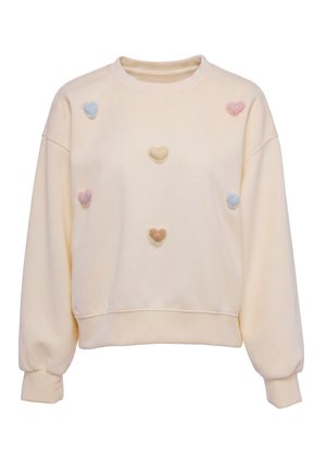 Cremefarvet sweatshirt med lange ærmer, dekoreret med små pastel-hjertepatches i blå, gul, lyserød og beige på forsiden.