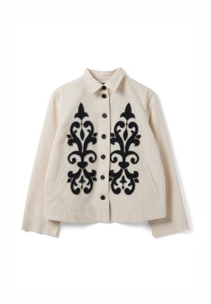 Chaqueta beige abotonada con cuello, bordado ornamental negro simétrico en el frente y bolsillos laterales.