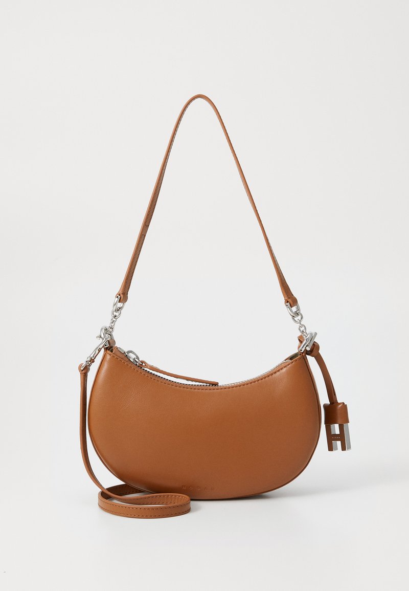 Borsa a tracolla in pelle marrone a forma di mezzaluna, con chiusura a zip e minuteria in argento. Presenta una tracolla rimovibile e un'etichetta decorativa.