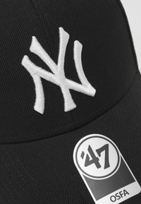 Casquette de baseball noire avec logo "NY" brodé en blanc. Présente un design structuré et une étiquette de taille indiquant "OSFA". Texture de tissu lisse.