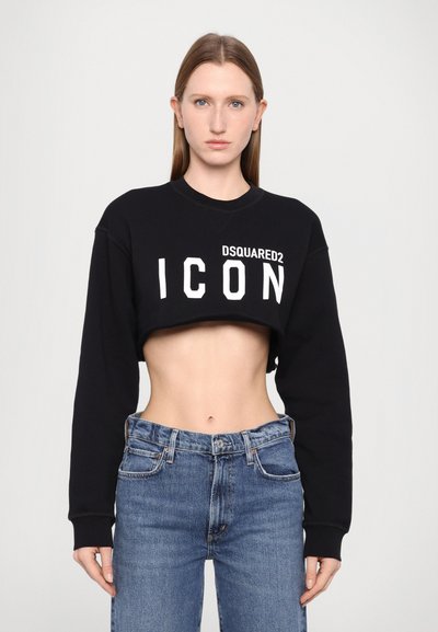 Schwarzes, tailliertes Sweatshirt mit weißem "DSQUARED2 ICON"-Grafik; mit langen Ärmeln und rundem Halsausschnitt, kombiniert mit faded blauen High-Waist-Jeans.