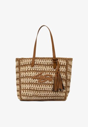 Bolso tote tejido en beige y marrón con asas de cuero marrón, detalle de borla y firma decorativa en cuero en el frente.