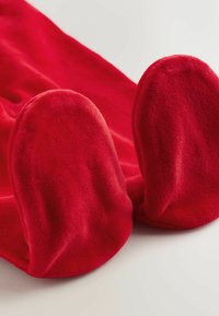 Coperta in pile rossa con estremità arrotondate, texture soffice e finitura liscia. Il tessuto appare spesso e accogliente, adatto per il calore.