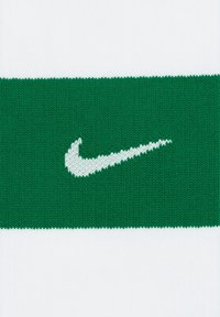 Fascia in grado di assorbire l'umidità di Nike con una fascia lavorata a maglia verde e un logo swoosh bianco su sfondo bianco.