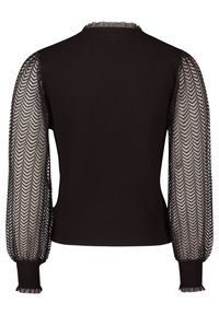 Mustaa villapaitaa, jossa on läpikuultavat, tekstuuriset hihat, joissa on herringbone-kuvio. Hihansuissa on ribbaus ja kaula-aukossa on röyhelöreuna.