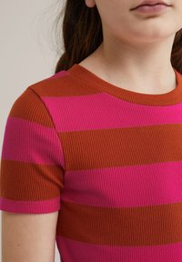 Sarkans un rozā svītrots adīts T-krekls ar īsām piedurknēm un apaļu kakla izgriezumu, ar ribota tekstūru un kontrastējošām horizontālām svītrām.