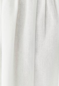 Ľahká biela tkanina s štruktúrovaným tkaním, s mäkkými záhybmi a jemnou difúziou svetla, vhodná na oblečenie alebo domácu dekoráciu.