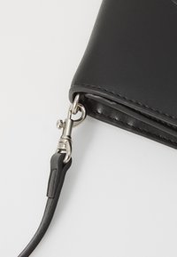Portafoglio in pelle nera con una trama liscia, caratterizzato da una clip metallica e una cinghia staccabile per il trasporto.